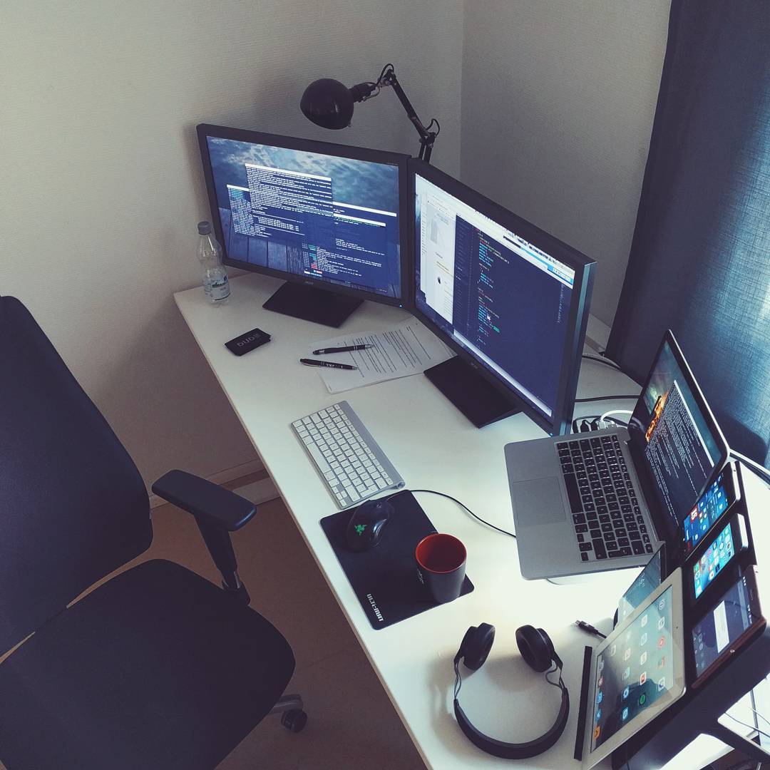 Office desk with all kinds of screens from small phones to iPads and computers.